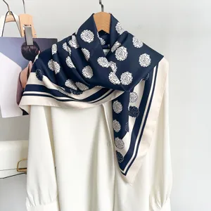 Eleganter Seidenschal mit Blumenmuster in Marineblau und Beige über einer weißen Bluse drapiert