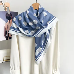 Eleganter blau-weißer Seidenschal mit Blumenmuster über einer weißen Bluse drapiert