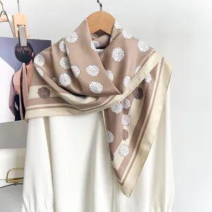 Detailansicht eines eleganten braunen Seidenschals mit floralem Muster über einem weißen Hemd