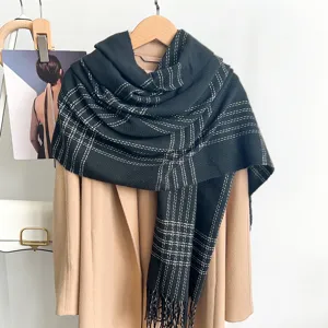 Vue détaillée d'une écharpe vintage à carreaux gris foncé avec franges sur un manteau.