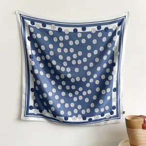Eleganter blau-weißer Seidenschal mit Blumenmuster an einer schlichten weißen Wand hängend