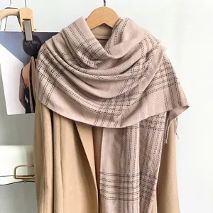 Vue détaillée d'une écharpe à carreaux beige en imitation cachemire avec des franges.