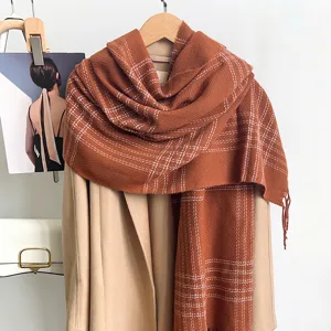 Gros plan détaillé d'une écharpe à carreaux marron vintage avec de doux glands.
