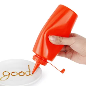 Gros plan d'une bouteille à presser en plastique rouge écrivant avec de la sauce sur une assiette