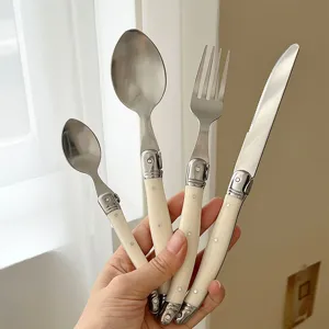 Close-up of 4-piece stainless steel cutlery set with elegant cream curved handles.