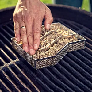 Detalle de caja ahumadora de acero inoxidable con pellets de manzano en la parrilla