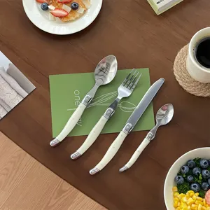 Four-piece cream white cutlery set with curved handles on a lifestyle wooden tabletop.