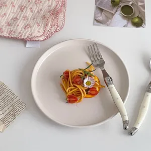 Close-up of elegant cream-handled stainless steel fork on a ceramic dinner plate