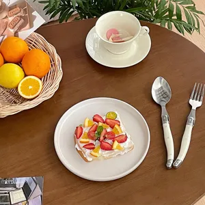 Elegant creamy white curved handle stainless steel fork and spoon on dining table.