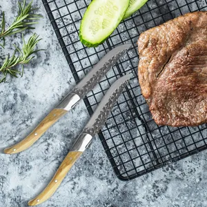 Detalle de cuchillos de carne estilo Laguiole con hojas martilladas y mangos de madera