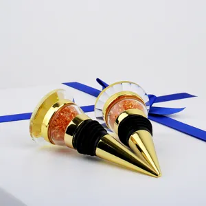 Close-up of elegant gold wine stoppers with orange crystal tops resting on a gift box