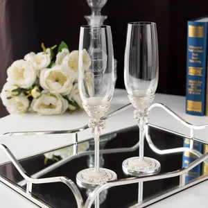 Détails de flûtes à champagne de mariage élégantes avec nœuds blancs et cristaux.
