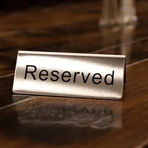 Gedetailleerde close-up van een roestvrijstalen Reserved-bordje met geborsteld staal.