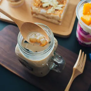 Nahaufnahme Detail von Holzlöffel und Gabel Set in gemütlicher Restaurant Szene mit Dessert.