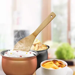 Natural bamboo rice spoon for non-stick pans shown in a warm domestic kitchen setting