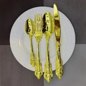 Detailed view of a vintage 4-piece gold cutlery set featuring ornate engraved handles on a plate