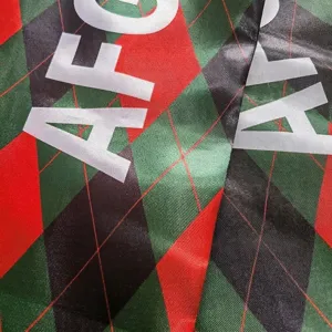 Détail macro d'une écharpe en satin polyester avec lettrage AFC et motif losange rouge vert