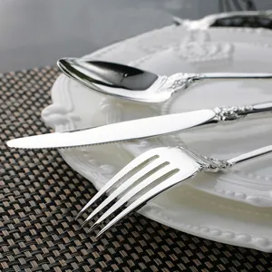 Detail of vintage silver cutlery set with elegant embossed handles on a white plate.