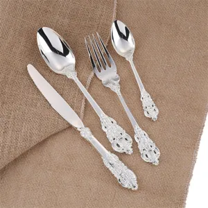 Detailed view of vintage silver cutlery set with ornate baroque floral handle carvings.
