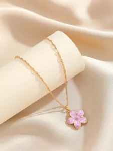 Elegant gold necklace featuring a delicate purple enamel flower pendant on silk background