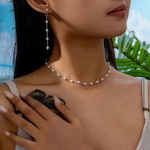 Elegante set di gioielli con collana e orecchini pendenti di perle, stile minimal.