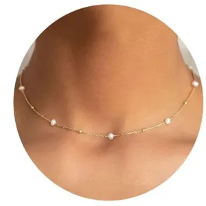 Gedetailleerde close-up van een delicate minimalistische parel choker ketting met gouden ketting.