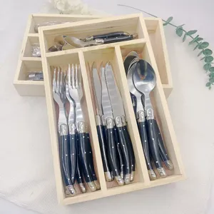 Detail of 24-piece Laguiole style cutlery set with black handles in a rustic wooden divider box