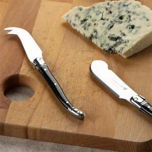 Nahaufnahme eines Laguiole-Käsemesser-Sets mit schwarzem Griff auf Holzbrett