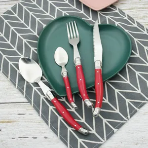 Red Laguiole-style cutlery set displayed on a dark green heart-shaped ceramic plate