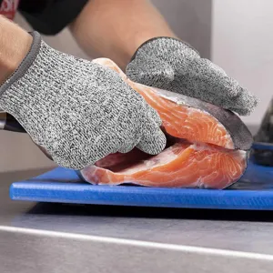Detail of level 5 cut resistant safety gloves handling fresh raw salmon in kitchen