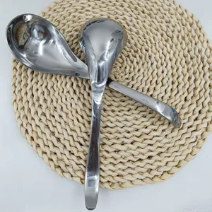 Close-up of thick stainless steel serving spoons with polished finish on woven mat