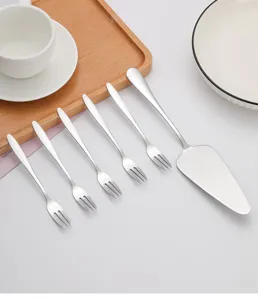 Vue détaillée d'une pelle à gâteau en inox et de 5 fourchettes sur une table blanche
