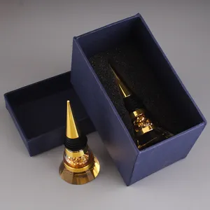 Detailed view of two gold cone wine stoppers with faceted crystal base in blue gift packaging