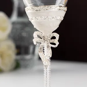 Gros plan d'un nœud blanc avec perles et cristaux sur un verre à champagne de luxe élégant