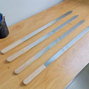 Nahaufnahme von langen Edelstahlspießen mit Holzgriffen, ordentlich auf Holztisch gelegt.