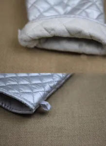 Detailed view of the thick heat-resistant lining and quilted silver surface of the oven mitt.
