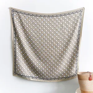 Detail of geometric square silk scarf with navy blue border and champagne beige patterns