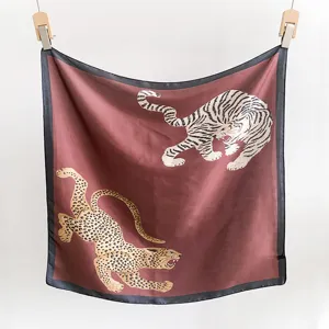 Foulard carré élégant en soie avec imprimés tigre et léopard sur fond rouge foncé.