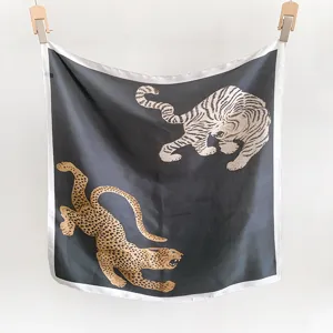 Détail d'un luxueux carré de soie noir orné d'imprimés tigres et léopards élégants.
