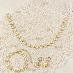 Bohemian daisy enamel jewelry set with necklace, bracelet, and earrings on lace background.