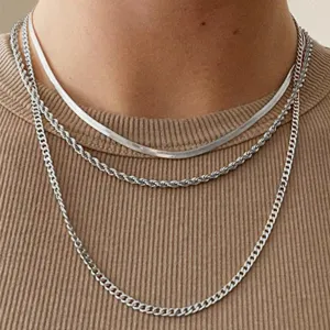 Primo piano dettagliato di collane a strati in argento: catena serpente, fune e barbazzale.