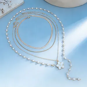 Detailed view of layered necklace set featuring white pleated flower pendant and beads