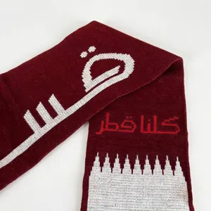 Close-up detail of a burgundy and white knitted flag scarf featuring Arabic script