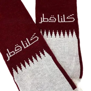 Close-up detail of maroon and white Qatar flag knitted scarf with jacquard Arabic text