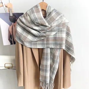 Detailed view of a warm grey and white plaid winter scarf draped over a camel coat