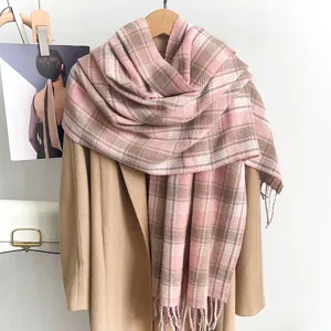 Detailed shot of a stylish pink and beige plaid winter scarf with fringe tassels.