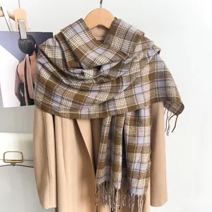 Close-up detail view of a warm brown and blue plaid winter scarf draped over a camel coat