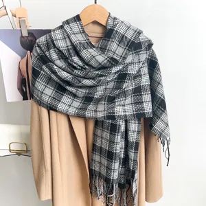 Detail of a classic black and grey plaid scarf with soft fringe tassels on a coat.