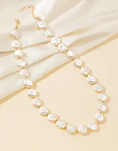 Dettaglio di una collana girocollo con perle piatte barocche e catena di estensione dorata