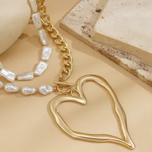 Close-up of a double-layer necklace with Baroque pearls and a molten heart pendant.